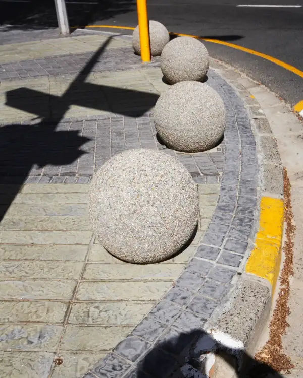 A run of Ball 500 spherical precast concrete bollards along a kerb
