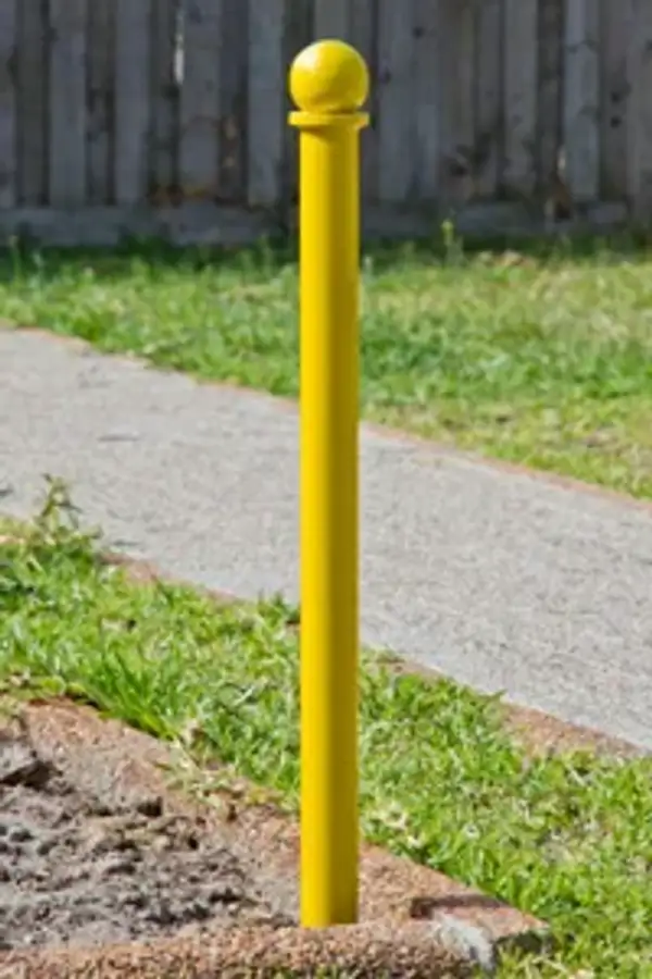 Slim Ball Head 50 steel bollard with a small ball-top cap, painted safety yellow, set at a garden path edge