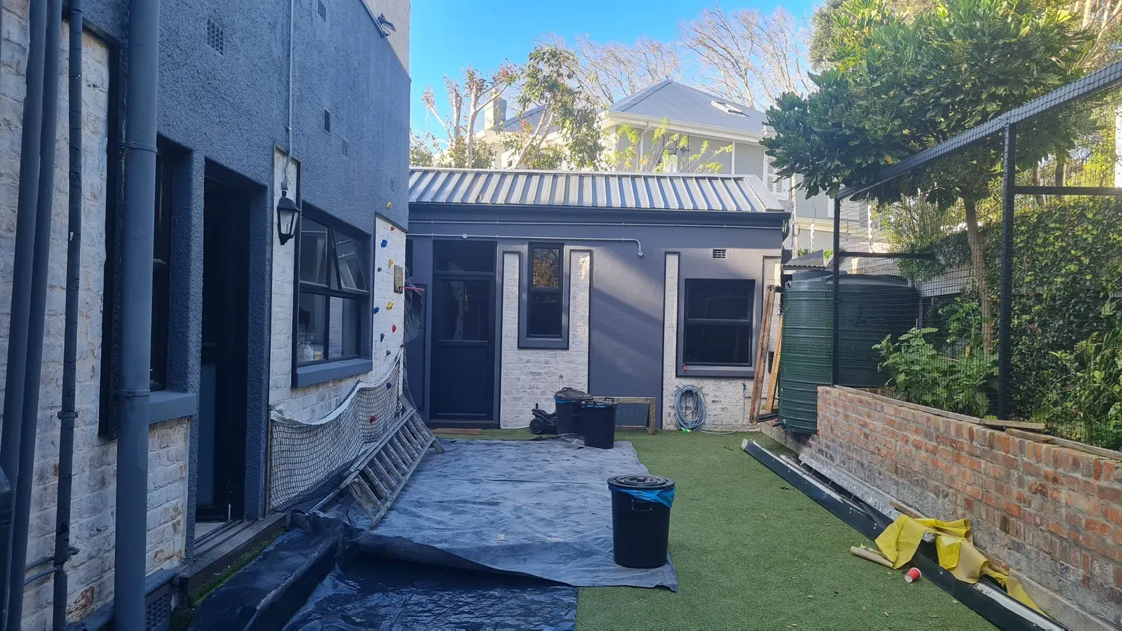 Finished standing-seam metal roof on an older painted-brick house, with new gutters and downpipes