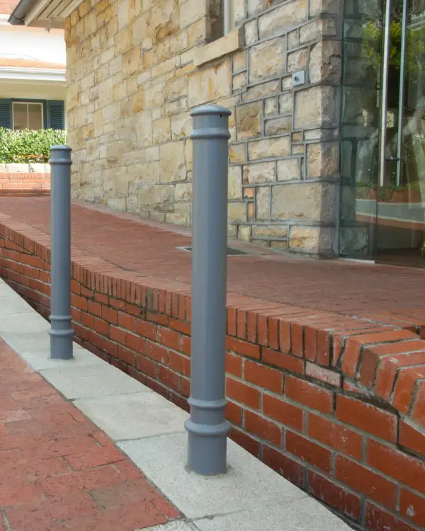 Newton decorative steel bollards with ribbed domed caps and base bands, installed along a brick-paved walkway