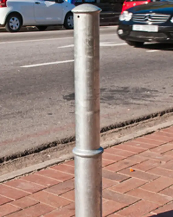Regal galvanised steel bollard with a domed top and a raised base band, set in brick paving at a kerb