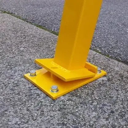 Square-section steel bollard hinged to a bolt-down flat base plate on a parking deck