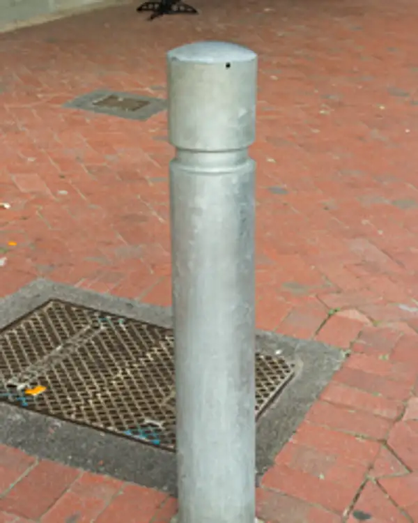 Round 150 convex-top galvanised steel bollard set into brick paving
