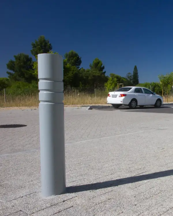 Round 150 tri-band powder-coated steel bollard at the edge of a parking area