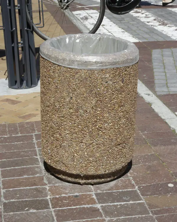 Round 500 precast concrete open-top litter bin with a bag liner over the rim, on street paving