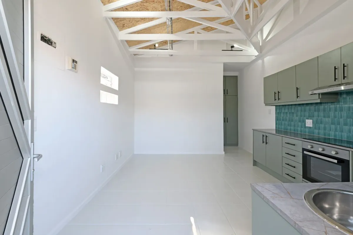 The same Wynberg space after the renovation, open plan with exposed white roof trusses