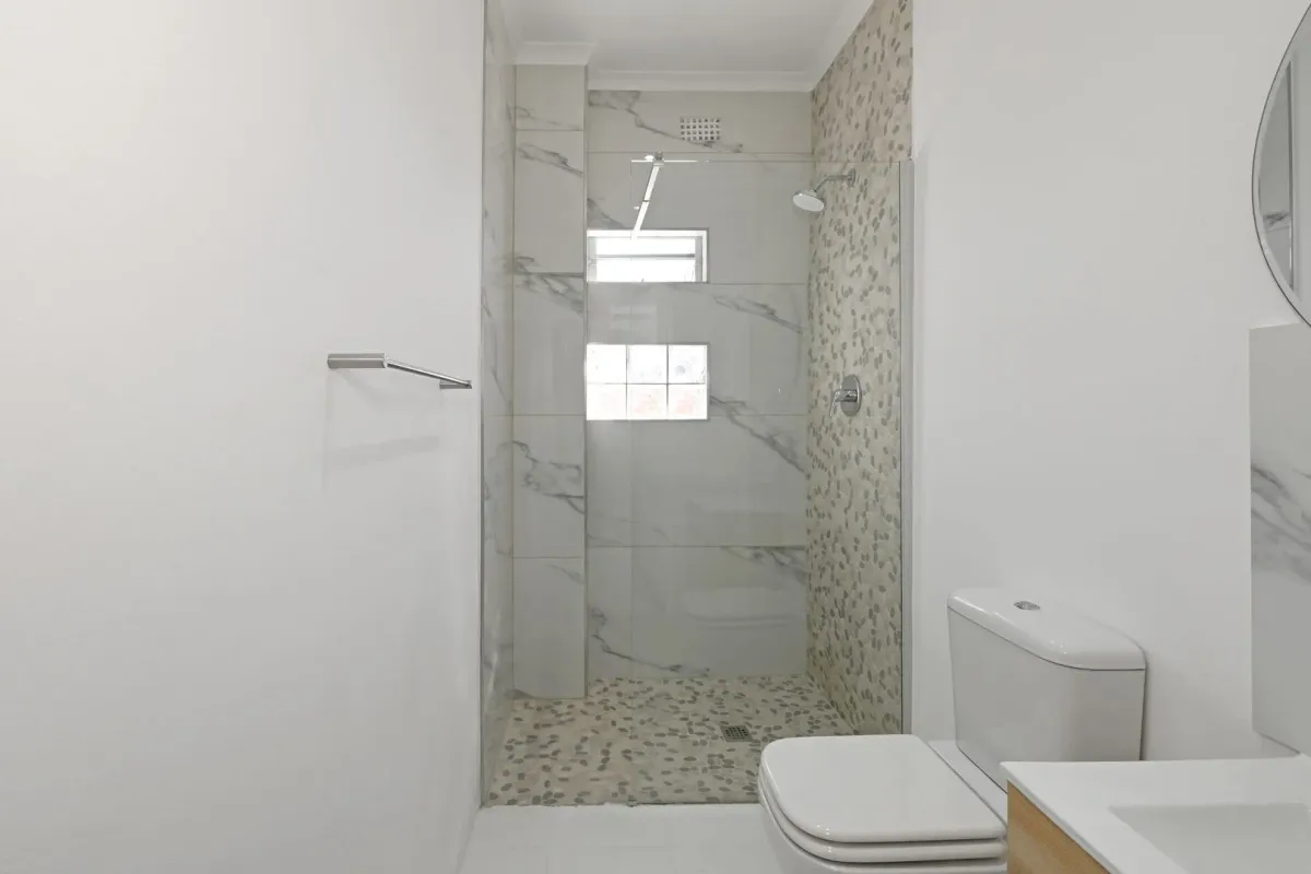 The Wynberg bathroom after the renovation, a walk-in shower with marble and pebble tiling