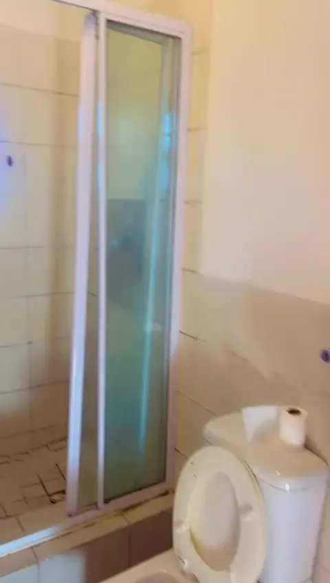 The Wynberg bathroom before the renovation, an old sliding-door shower and dated tiling